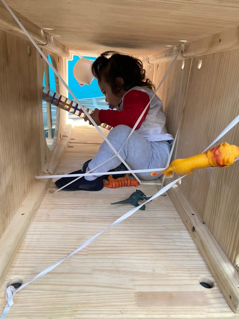 Criança explorando cabana de madeira com brinquedos