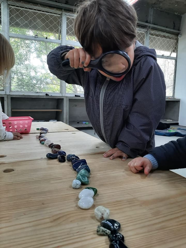 Criança investigando pedras com lupa
