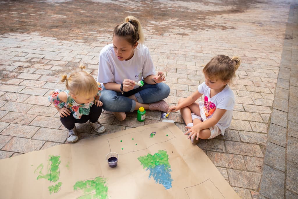 Educadora Ludique pintando com duas crianças